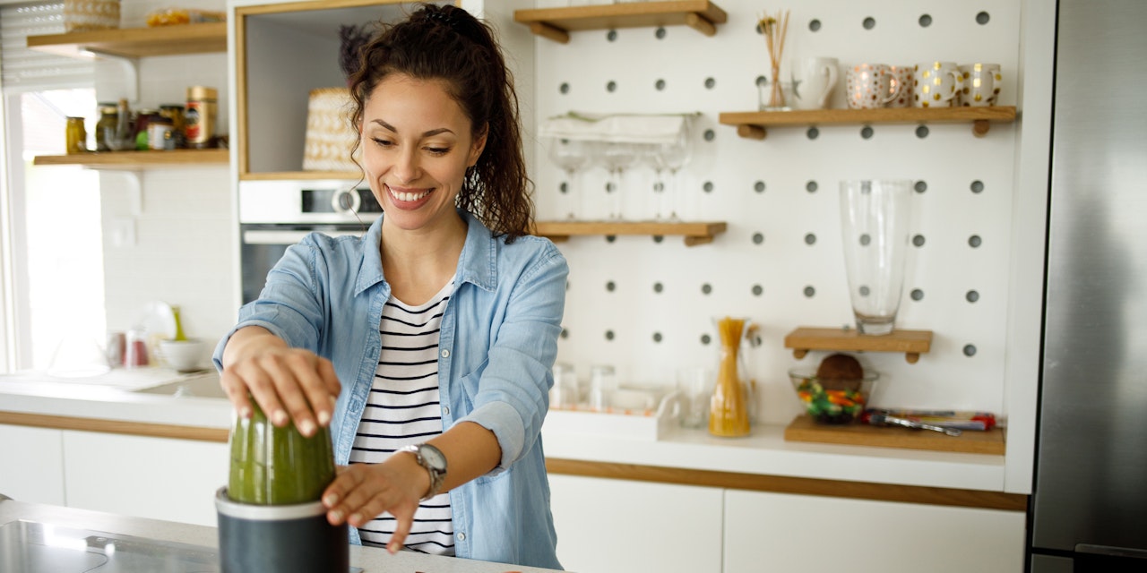 Happy woman making green juice