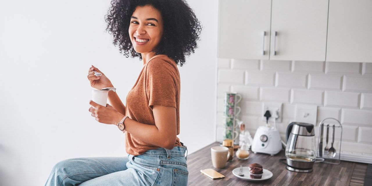 Woman eating yogurt at her kitchen