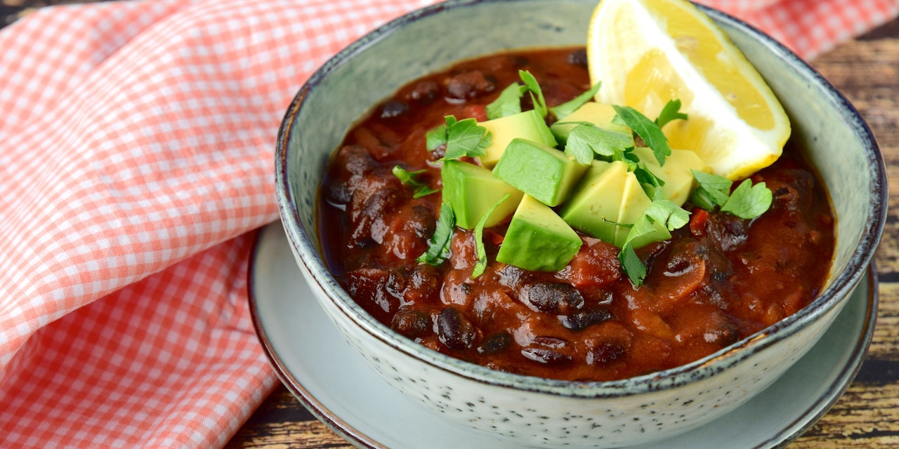 Bowl of bean and tomato chilli with avocado and lemon