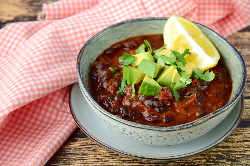 Bowl of bean and tomato chilli with avocado and lemon