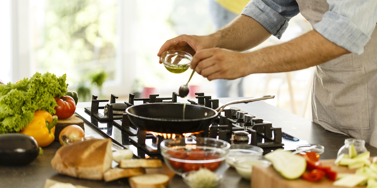Man pouring healthy cooking oil into frying pan