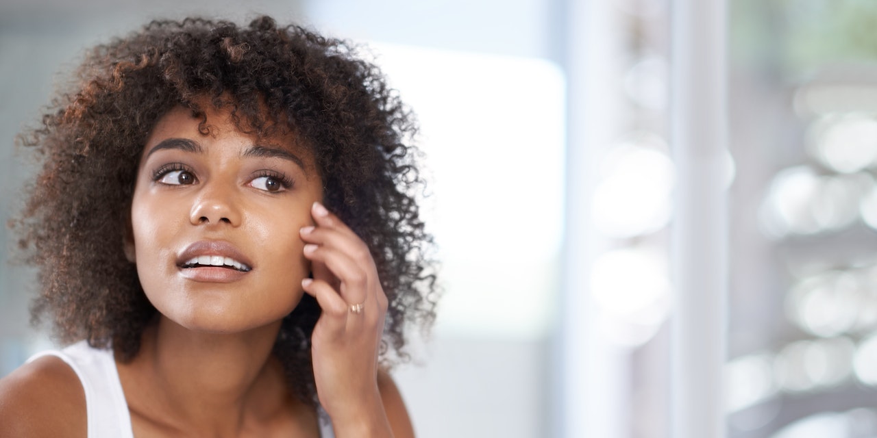 Woman looking at her skin in the bathroom  mirror