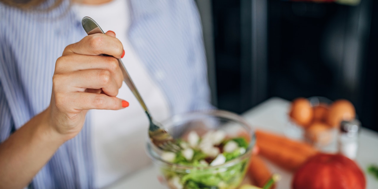 Woman eating a small leafy salad