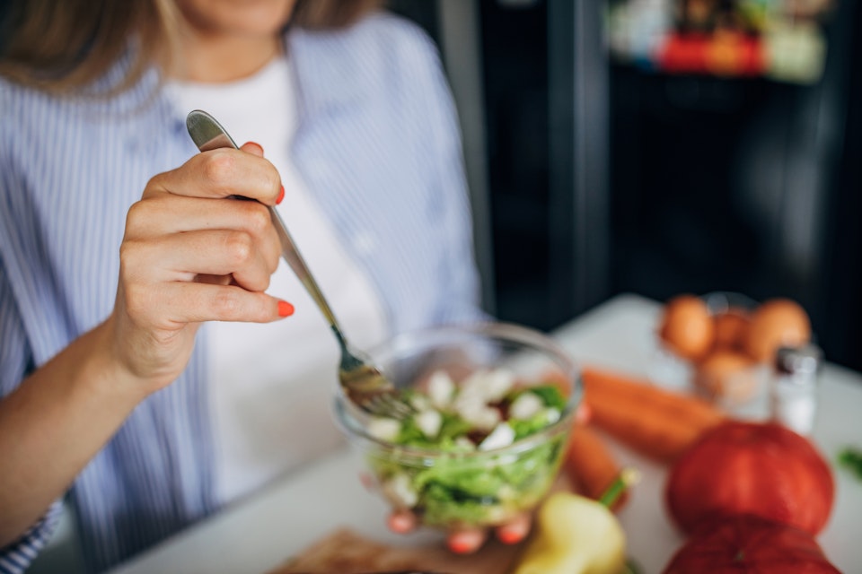 Woman eating a small leafy salad