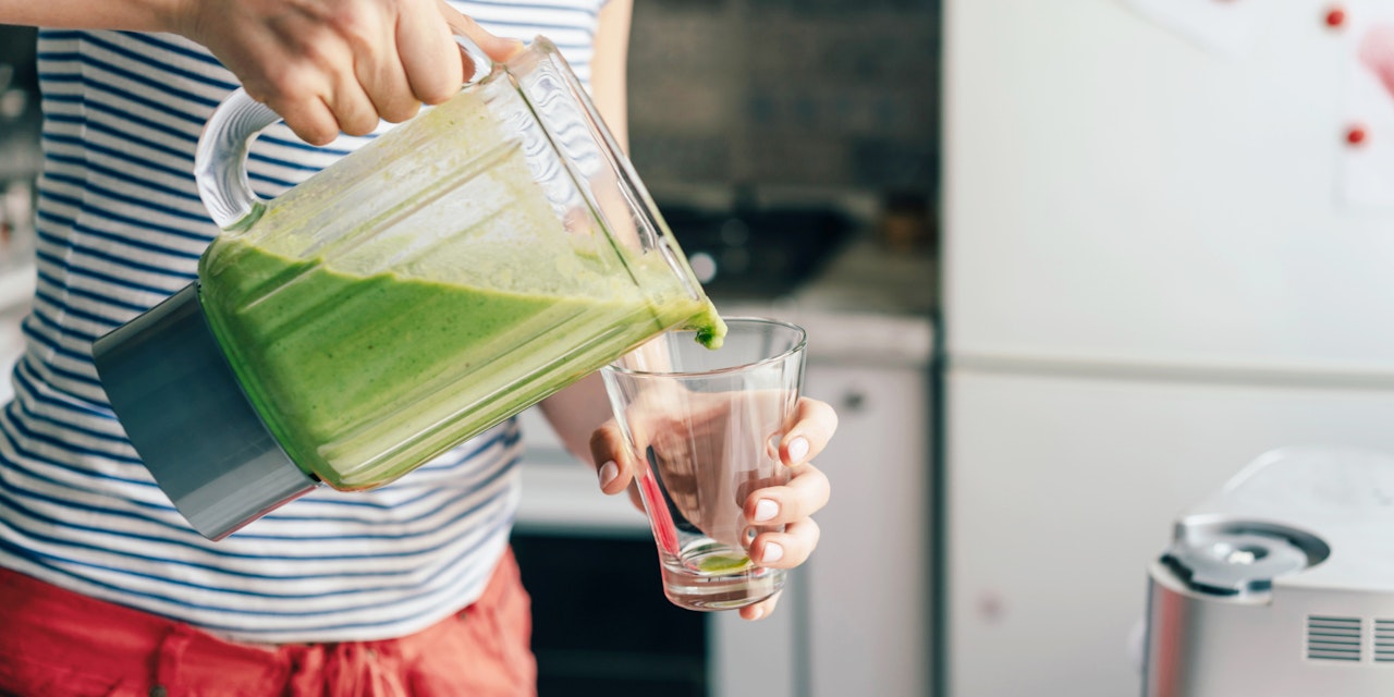 Woman pouring green juice Woman pouring green juice into a glass