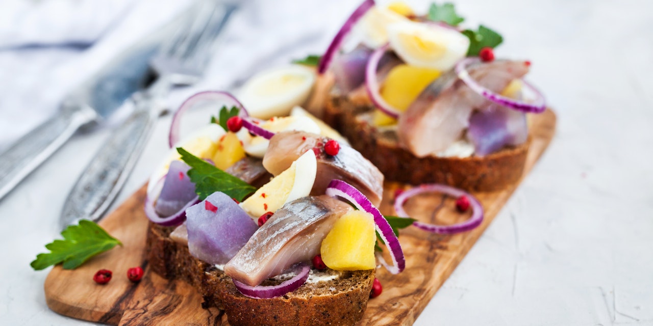 Smørrebrød with rye bread, herring, onion, potato and eggs