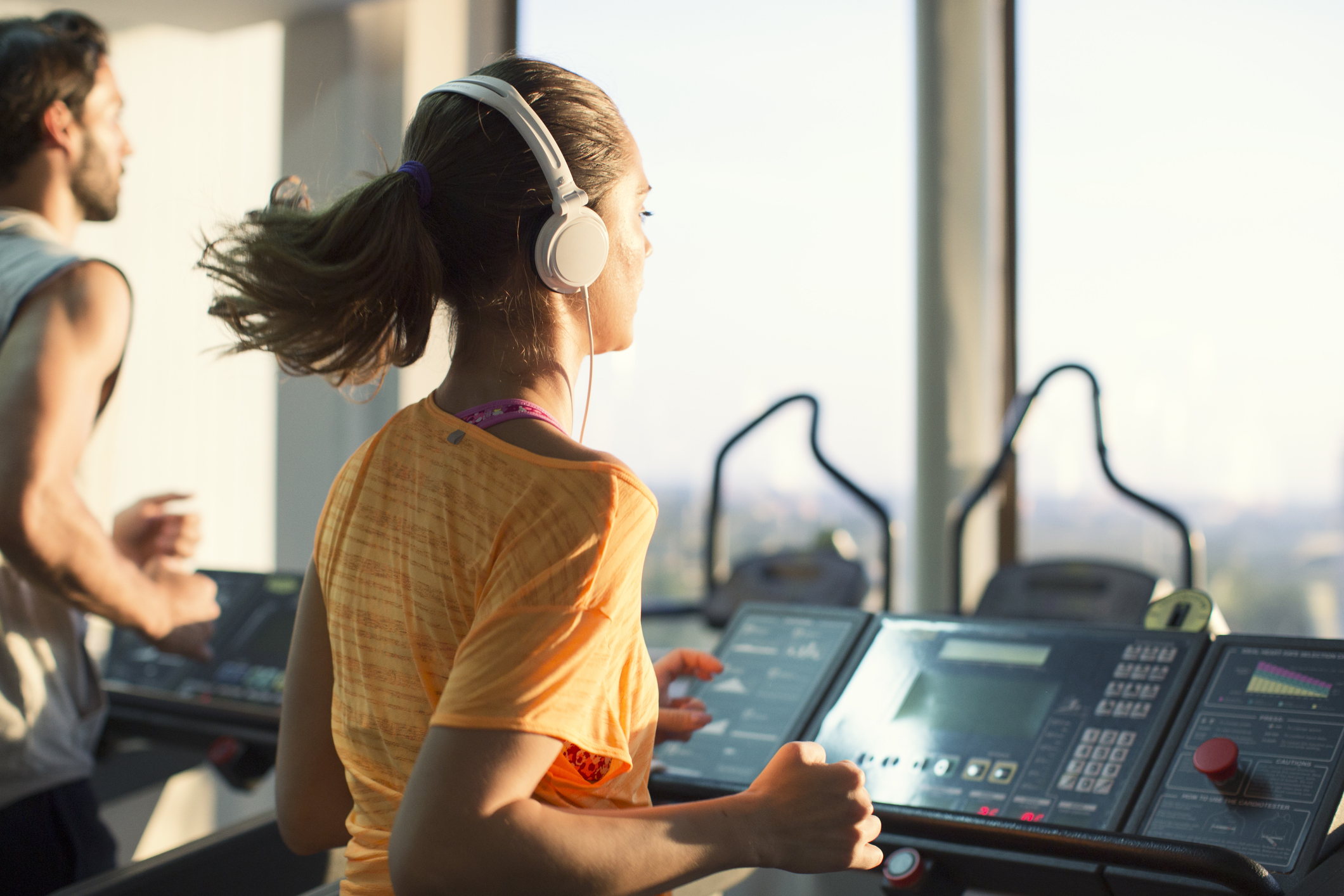 Woman with headphones running on the treadmill at the gym