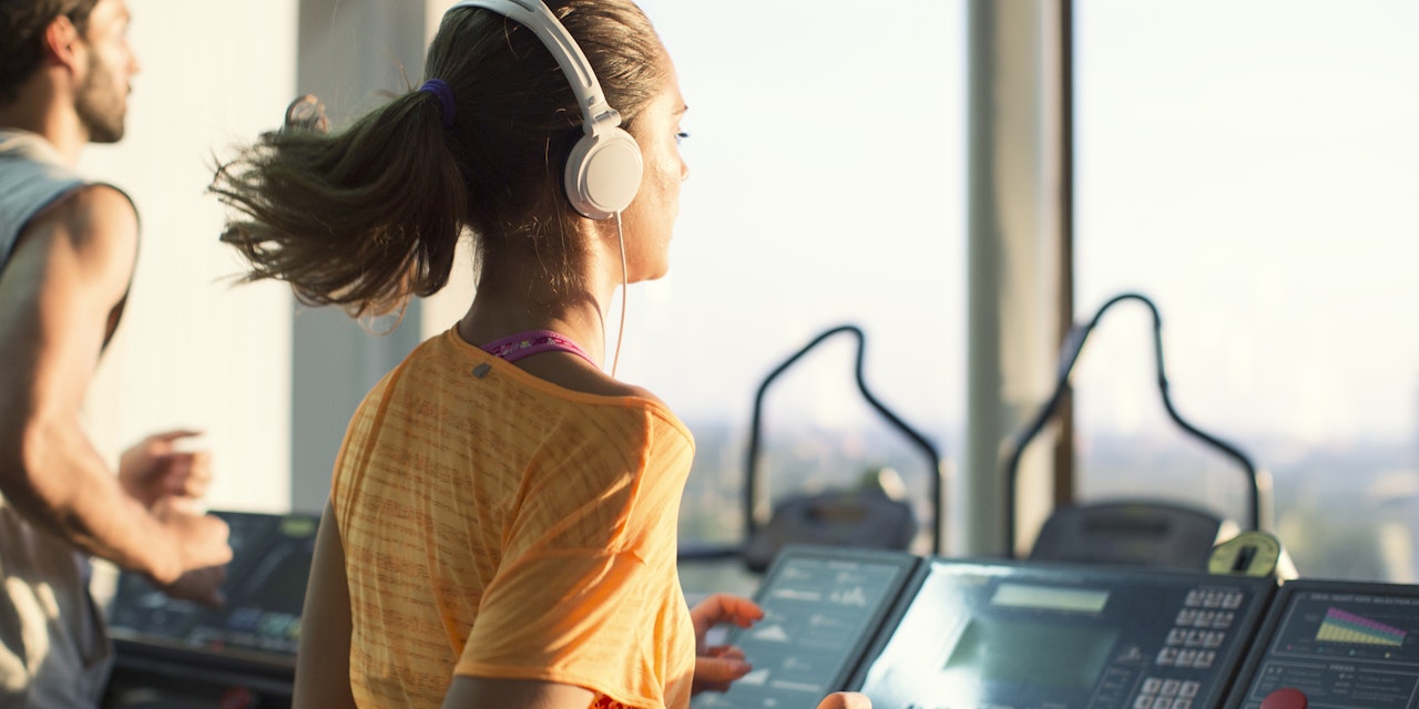 Woman with headphones running on the treadmill at the gym