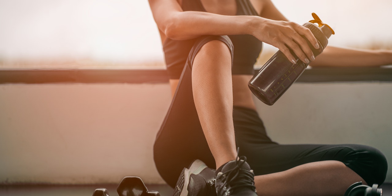 Woman relaxing after a workout and drinking whey protein