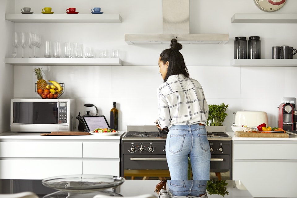 Woman cooking and checking the recipe in her tablet