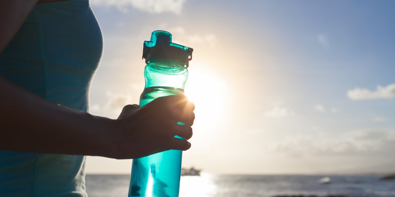 Person holding a water bottle outdoors after workout