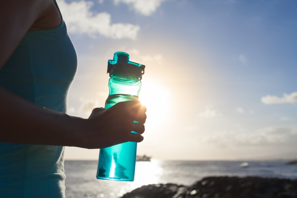 Person holding a water bottle outdoors after workout
