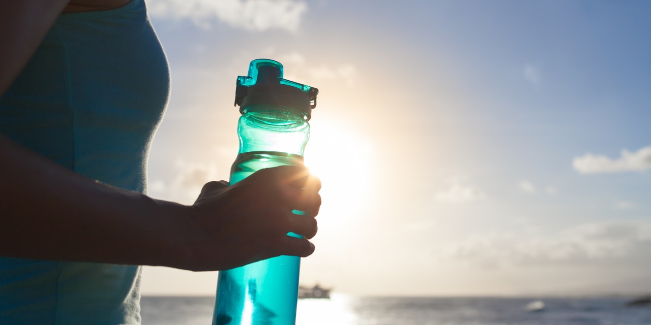 Person holding a water bottle outdoors after workout