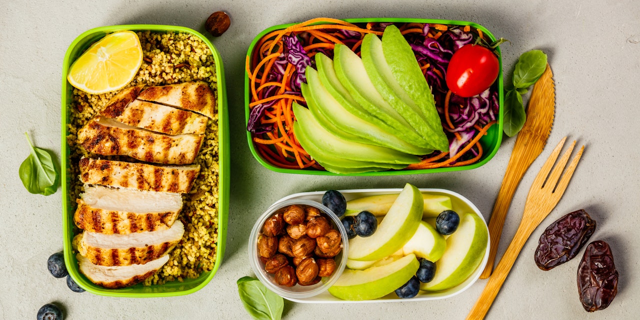 Healthy meal prep containers with couscous, grilled chicken breast, salad, avocado and fruits.