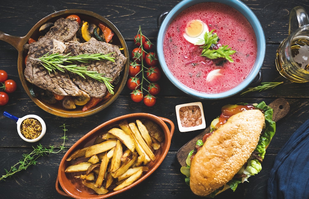 Meat, potato, soup and sandwich on a wooden table