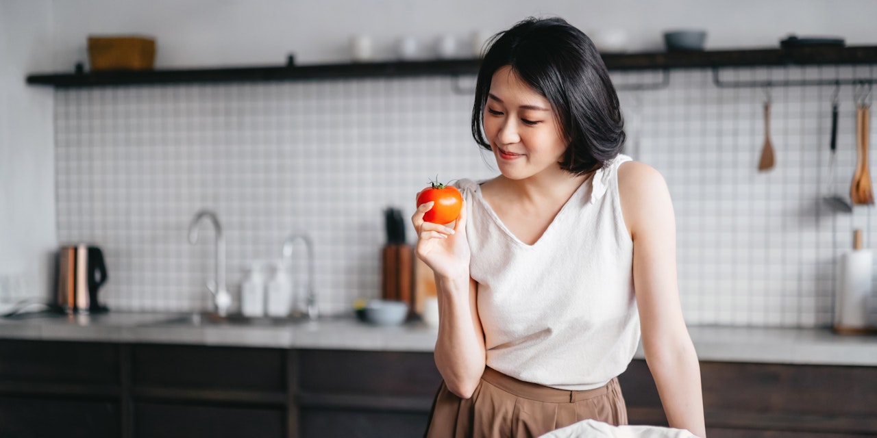 Woman holing a tomato Vegetables are a staple of sustainable food shopping