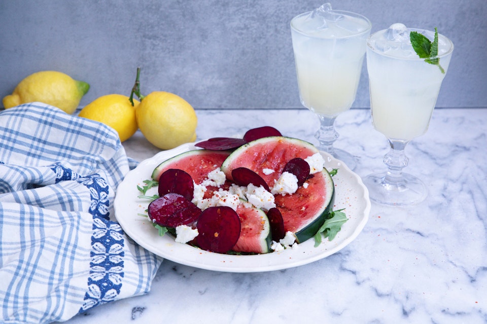 Grilled watermelon salad with beets, cheese, and drinks on the side