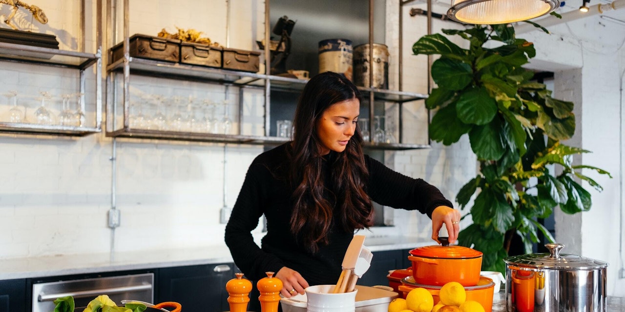 Cooking foods for better nutrient absorption Woman cooking with powerful food combinations in a rustic-inspired kitchen