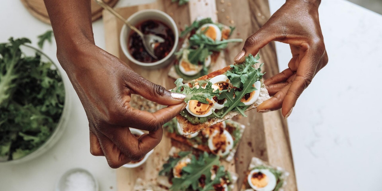 Uncover the facts and myths of nutrition A person holding a piece of toast with eggs, rocket, and other healthful foods.