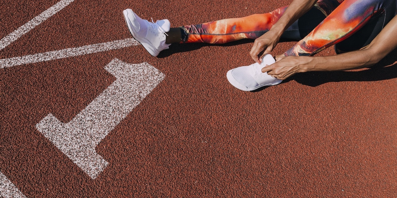 Marathon season is approaching! Girl tying her shoes on running track