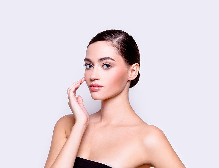Young woman gently touching her cheek