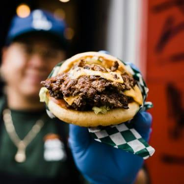 A staff member holds a double cheese smash burger out to the camera