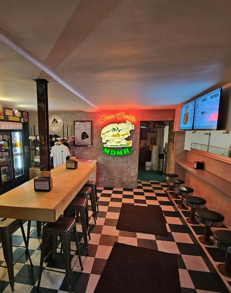 The casse-croûte dining room with checkered floor and neon sign