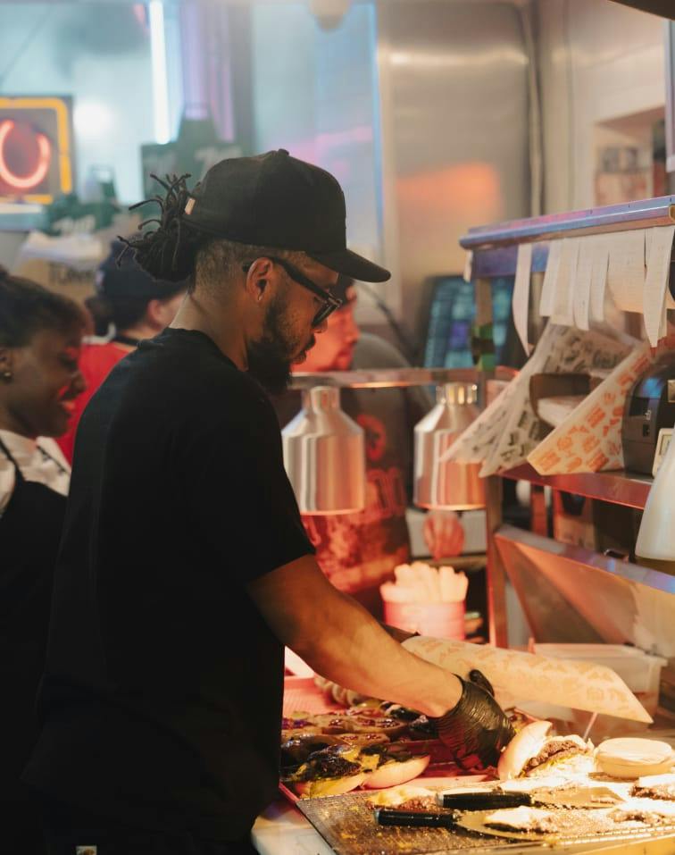 A cook making burgers on the griddle