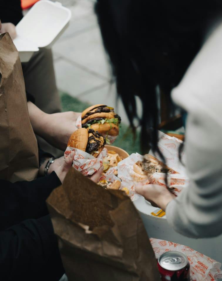 A customer holding a smash burger over their bag