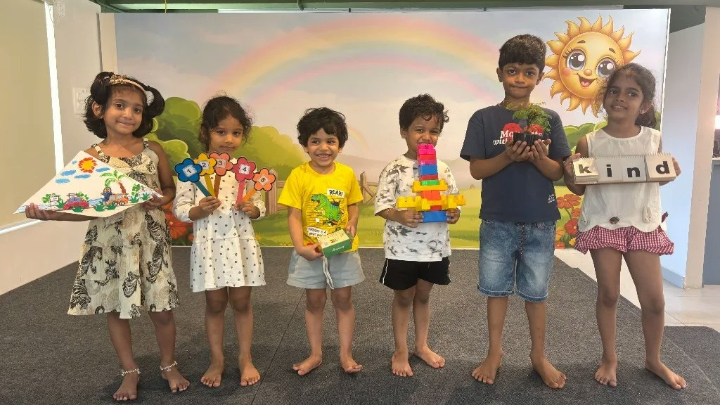 Six ULTRA_school children holding up the projects they made, in front of a rainbow mural