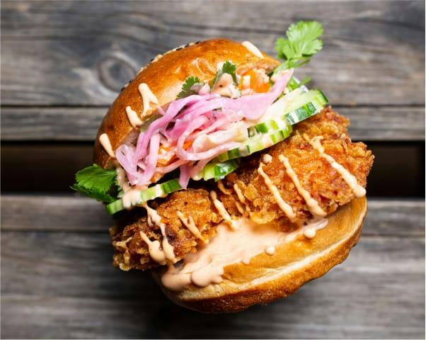 Burger au poulet frit, légumes marinés, concombre et coriandre