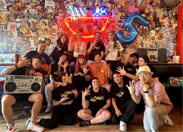 L’équipe de La Belle Tonki réunie devant le mur de collages et le néon du restaurant