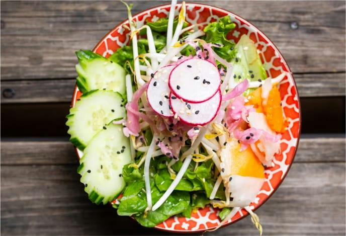 Salade de légumes croquants, radis et concombre dans un bol orange