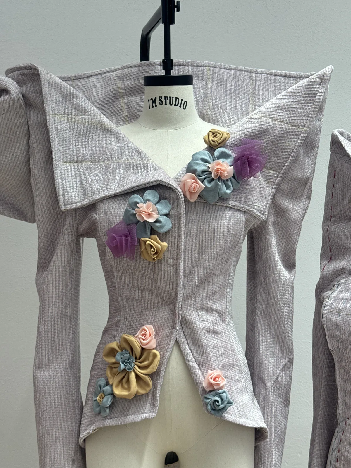 Capo sartoriale con decorazioni floreali su manichino