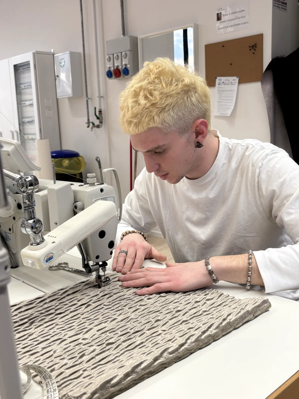 Studente al lavoro su un tessuto lavorato alla macchina da cucire