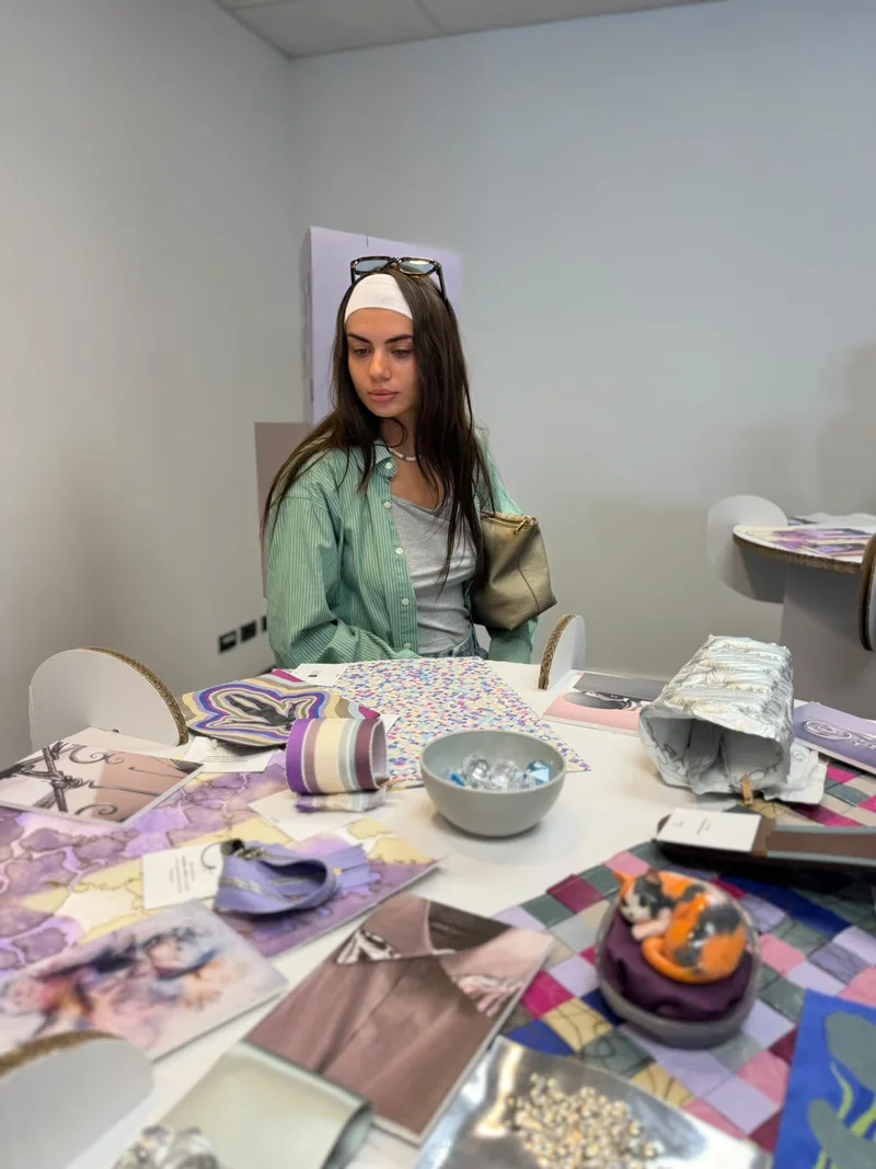 Studentessa osserva una raccolta di materiali e progetti moda