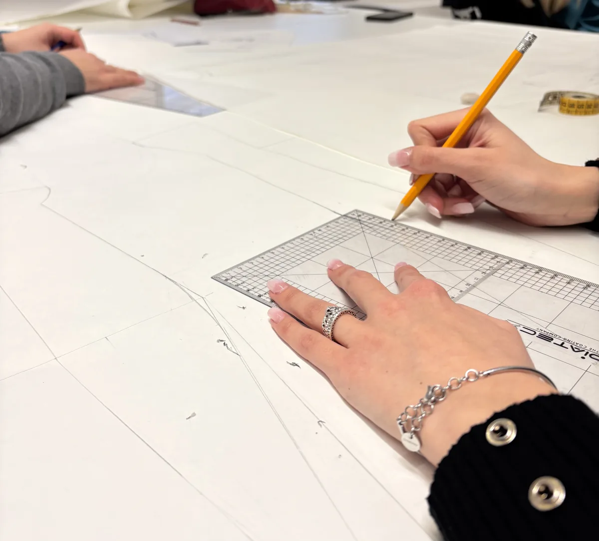 Disegno di un cartamodello con matita e squadra nei laboratori MITA