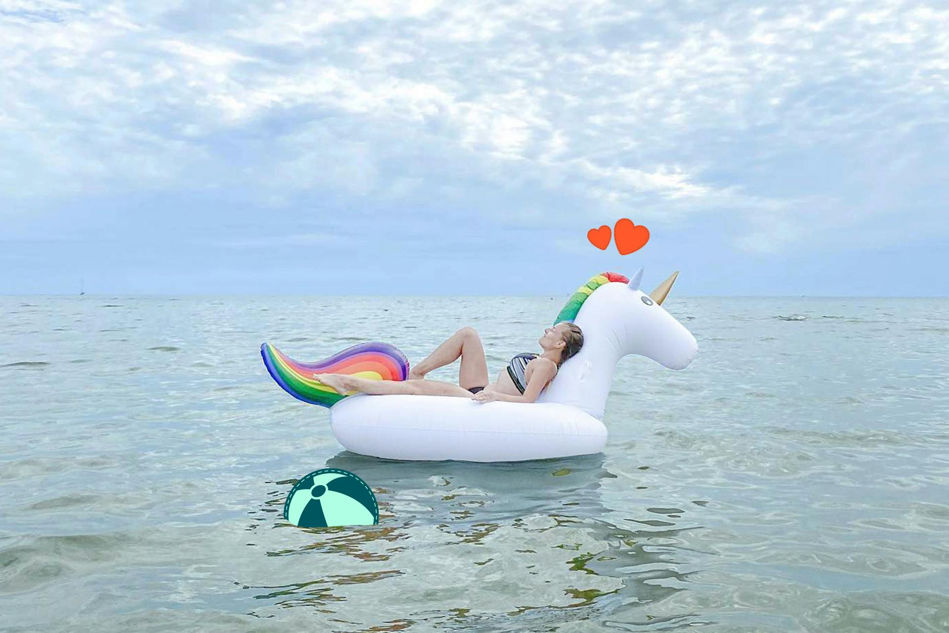 Frau die sich im Meer auf einem aufblasbaren Badeanzug in Form eines Einhorns entspannt