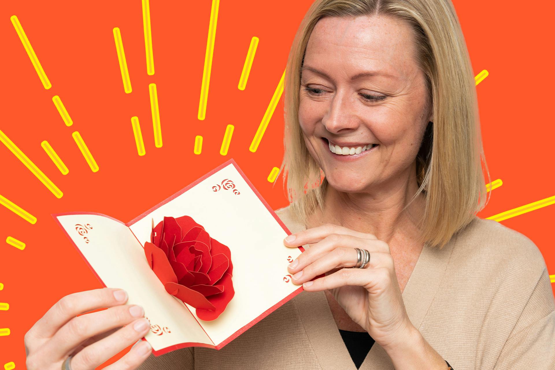 Glad kvinne åpner et popup-kort med en rose