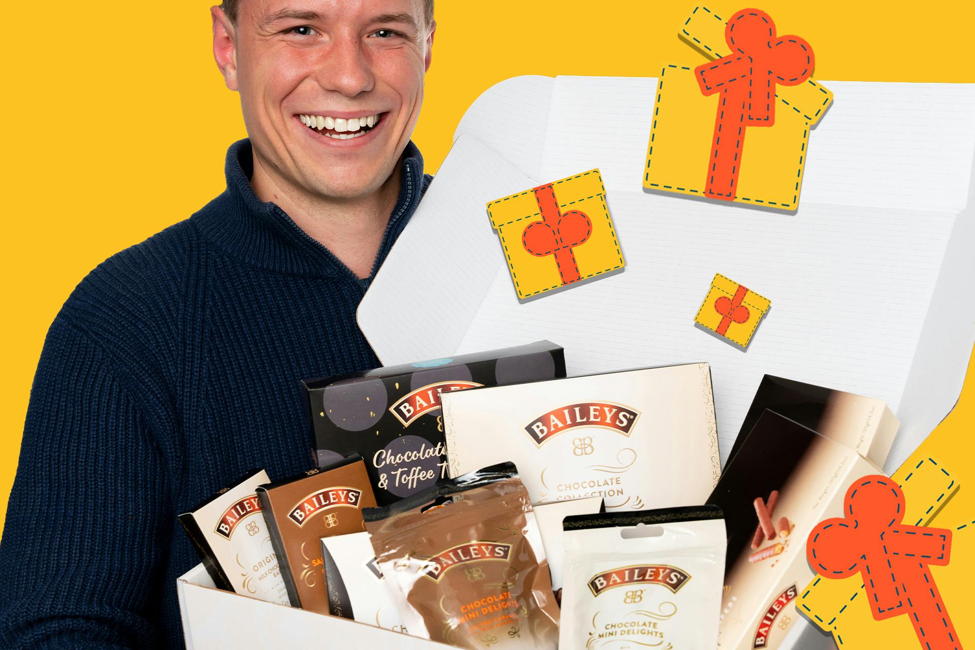 Glücklicher Mann, der eine große Geschenkbox voller Süßigkeiten und Schokolade hält