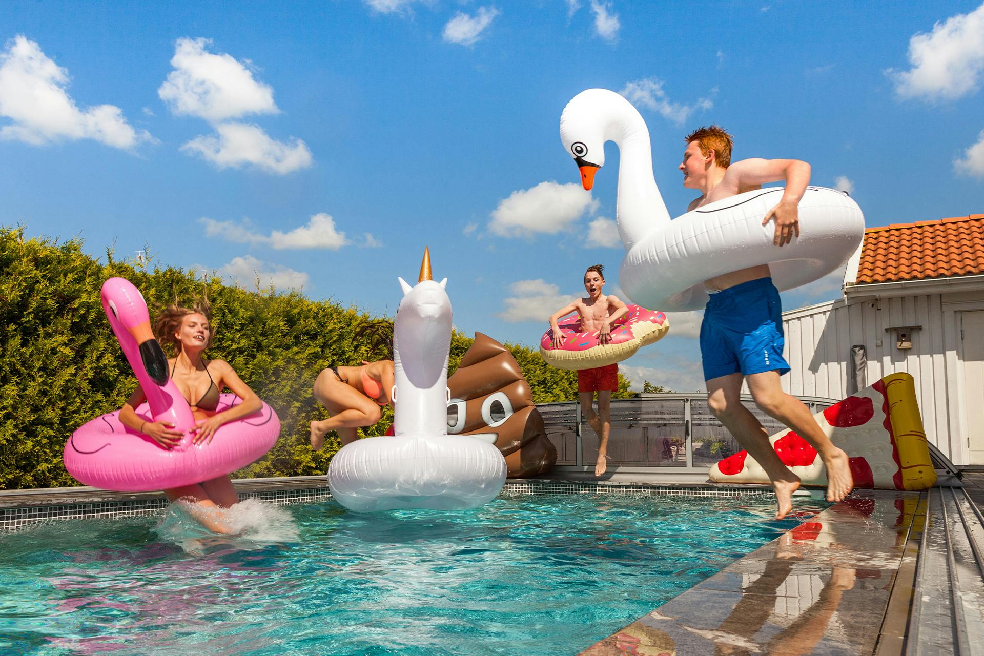  Glückliche Menschen im Pool mit aufblasbaren Badeanzügen und Spielzeug