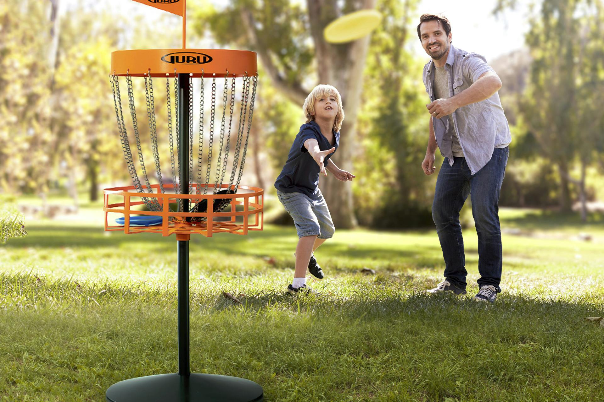 Man och barn spelar frisbeegolf utomhus i naturen 