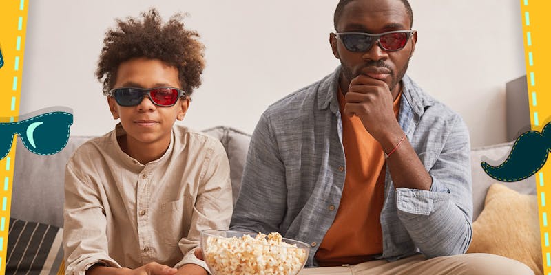 Vater und Sohn sitzen mit Popcorn auf dem Sofa