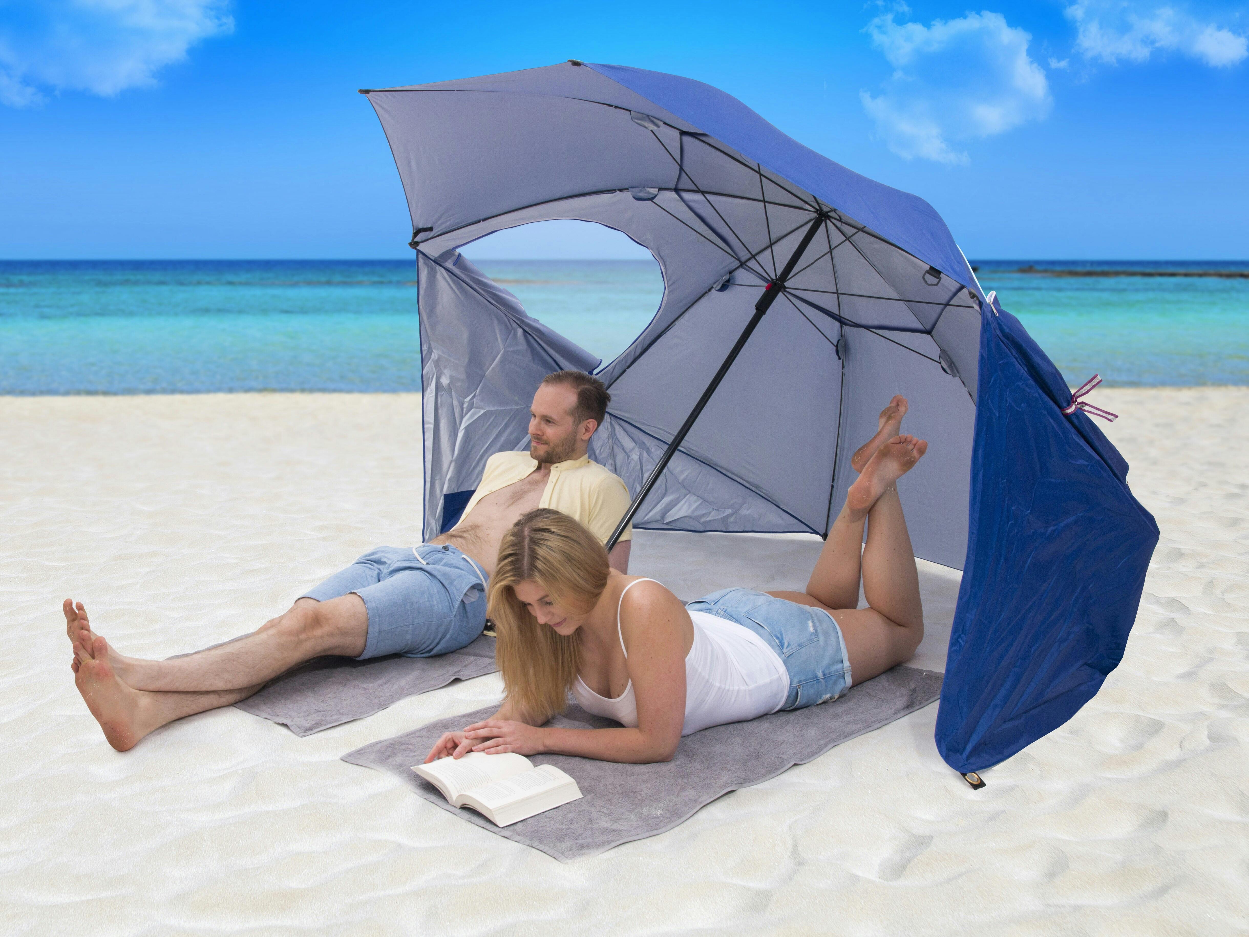 Två personer på en strand med ett stort parasoll