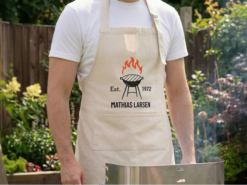 Et forklæde i høj kvalitet med et personligt navn trykt på brystet, perfekt til madlavning eller grill