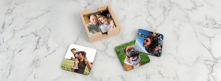 Personliga glasunderlägg med egna foton på familj och husdjur liggandes på en marmorskiva.