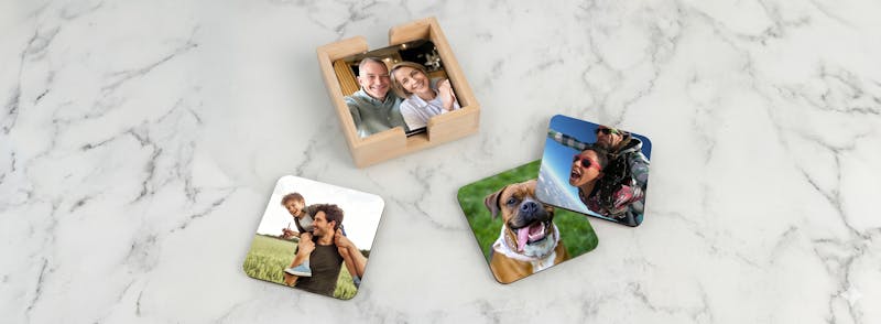 Personliga glasunderlägg med egna foton på familj och husdjur liggandes på en marmorskiva.