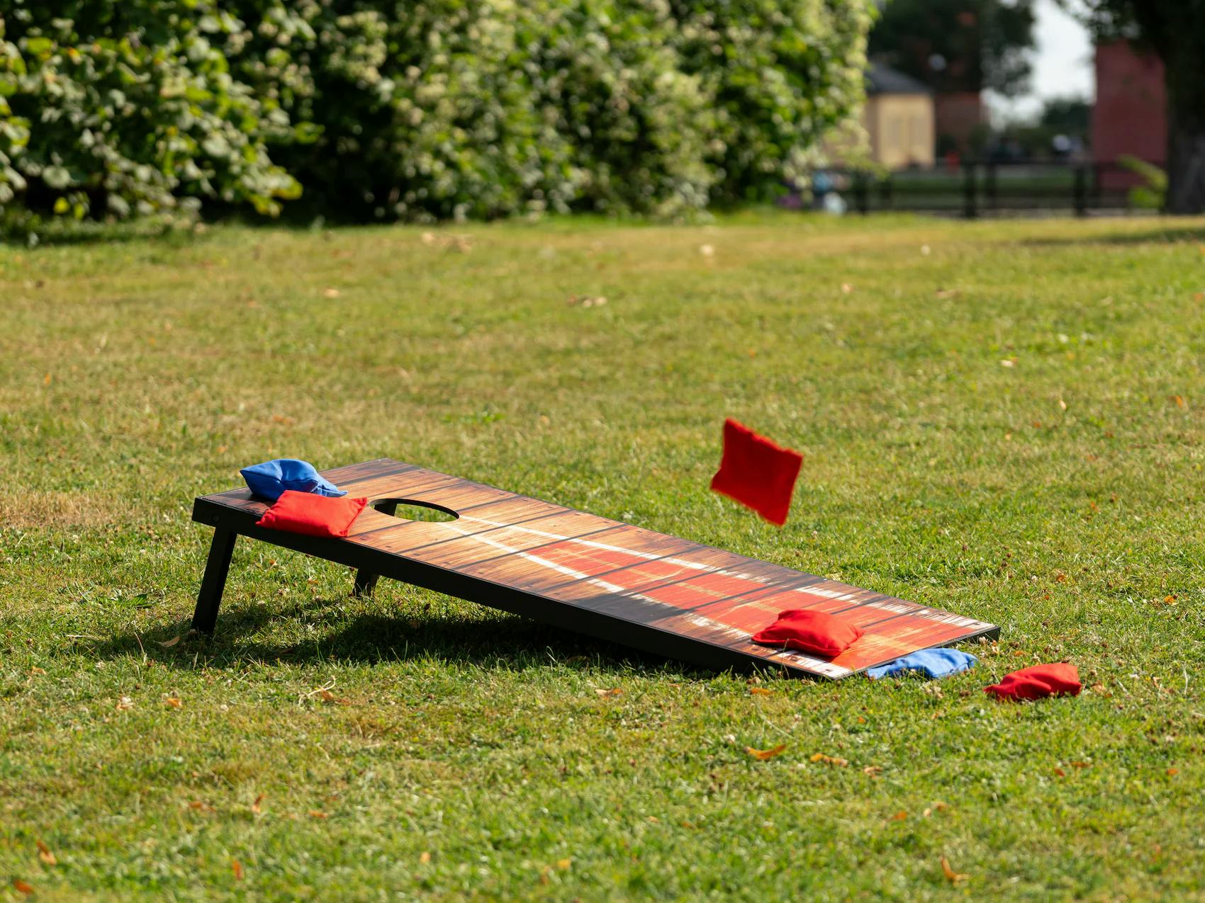 Cornhole-pihapeli ja hernepussit nurmikolla, hauska ulkolelu koko perheelle