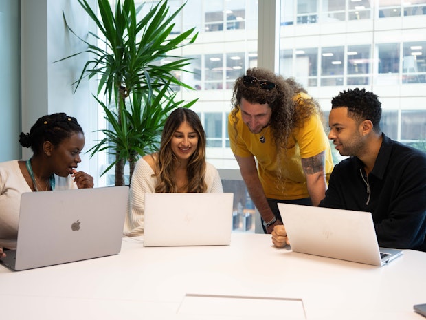 Four Zopa employees gather around their laptops