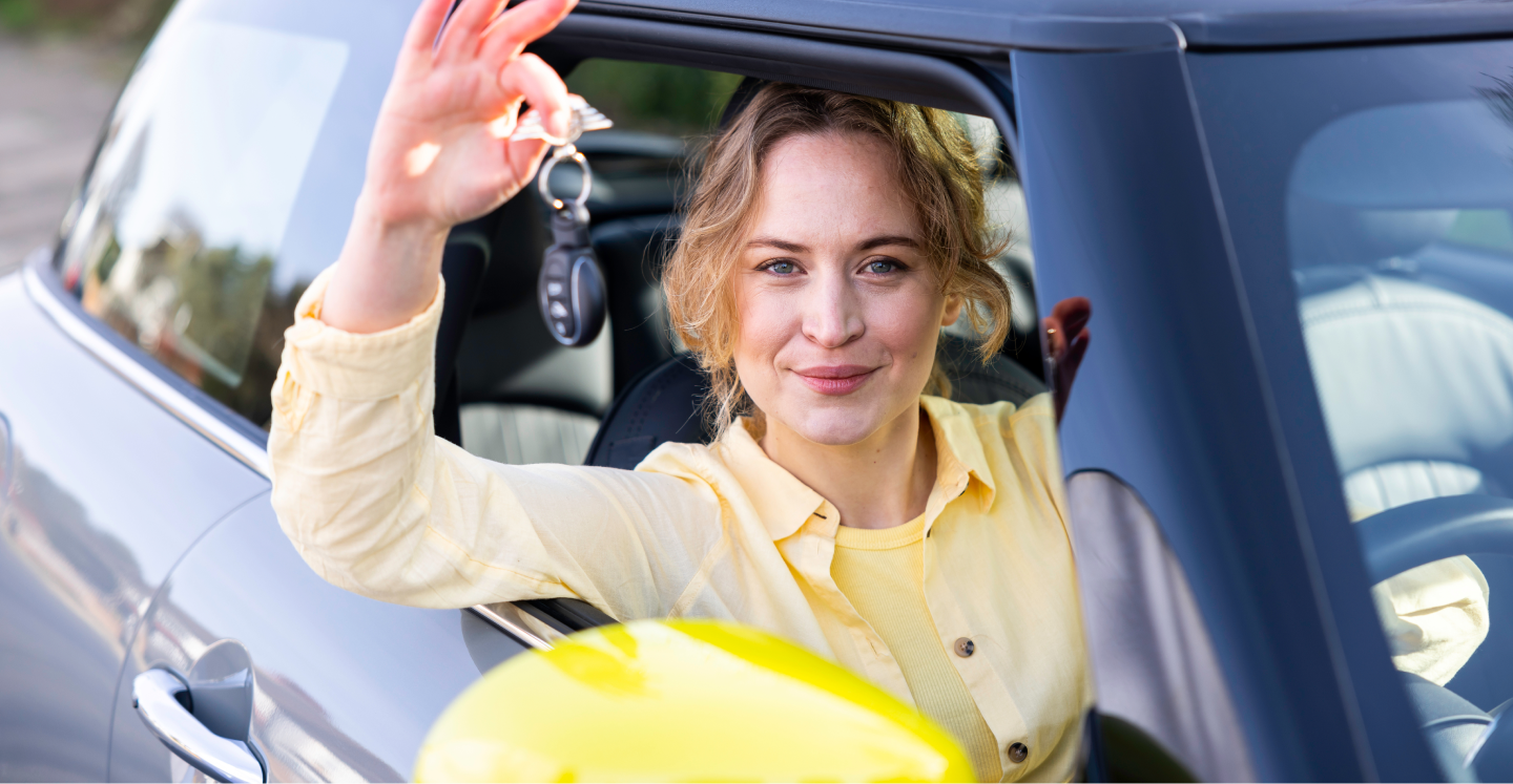 A woman sitting in a car holding the keys to the vehicle